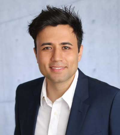 Portrait von Dr. Farhad Holm mit grauem Hintergrund